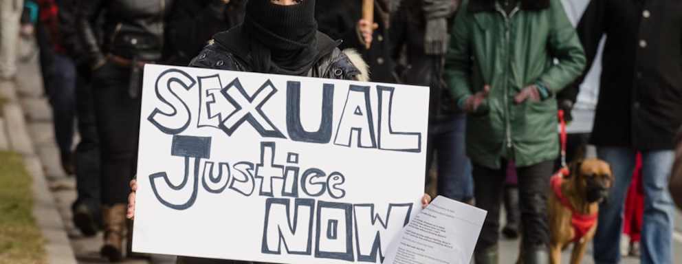 A woman carries a sign of protest while marching down University Avenue towards Dalhousie University during a student protest event. The protest happened after the discovery of a Facebook group allegedly operated by Dalhousie Dentistry students that contained comments about drugging and raping women, as well as other misogynistic and hateful posts.