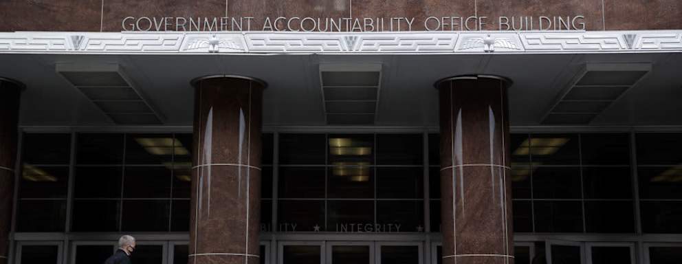 Pedestrians wearing protective masks walk by the U.S. Government Accountability Office