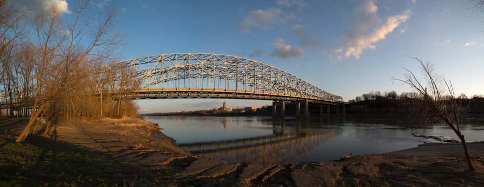 The Missouri Capitol building is reflected in the distance of the Missouri River underneath the Highway 54 bridge in Jefferson City, Missouri.