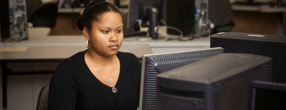 Black female student typing on a desktop computer in a community college computer lab.