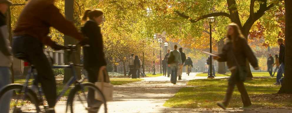 Students walking on footpaths on college campus, autumn