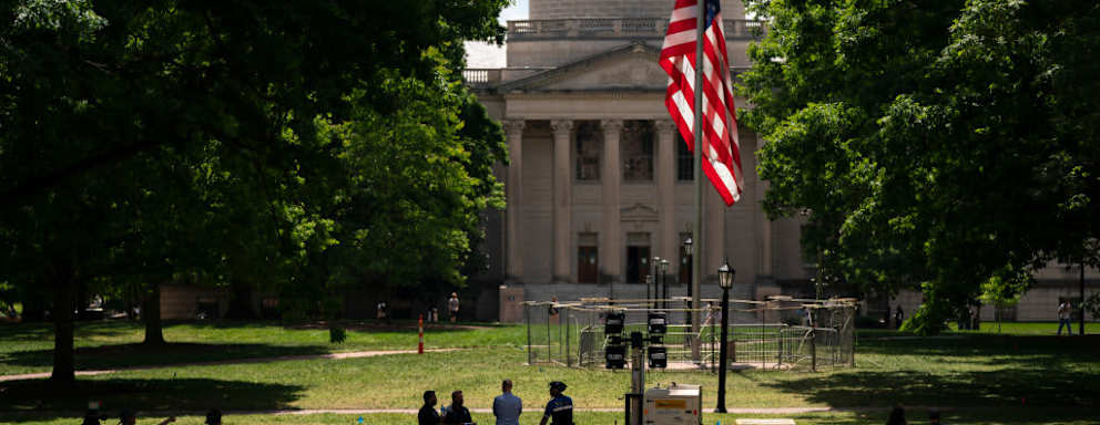 A chain link fence barricade surrounds the American flag at Polk Place on the University of North Carolina campus in Chapel Hill, North Carolina. On May 1, 2024, protestors removed an American flag and raised a Palestinian flag following a dispersement of an encampment at Polk Place.