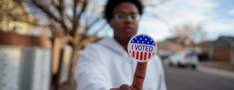 Young man holding I voted sticker