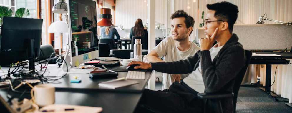 Male computer professionals programming on computer at tech-startup office