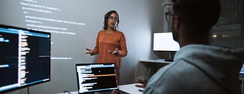 Hispanic Latin American software engineer developer use laptop computer program coding, projection screen presentation. Programming language development, business technology, night work people concept