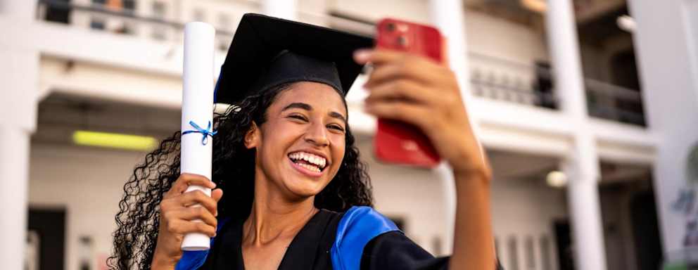 Young woman taking a selfie with her diploma on the graduation