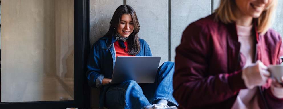 Two students studying together on laptops at a cafe.