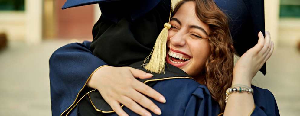 Graduates hugging at commencement