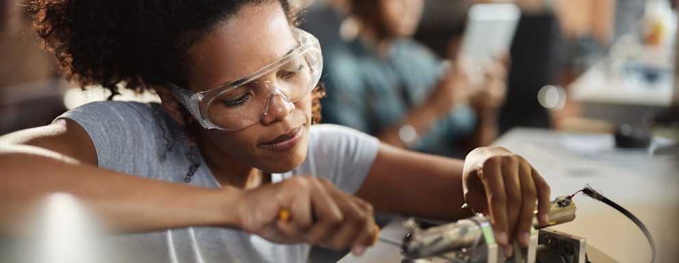 African American student of science repairing an electrical component in a lab.
