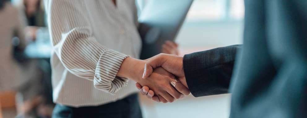 Two professionals shaking hands in a workplace