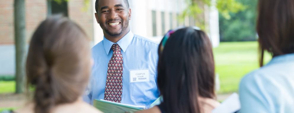 College campus tour guide talking with prospective students outdoors