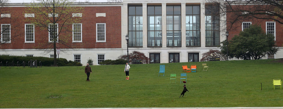 BALTIMORE, MARYLAND - MARCH 28: A couple throw a frisbee for a dog on the campus of The Johns Hopkins University on March 28, 2020 in Baltimore, Maryland. The school is shut down due to the coronavirus (COVID-19) outbreak. (Photo by Rob Carr/Getty Images)