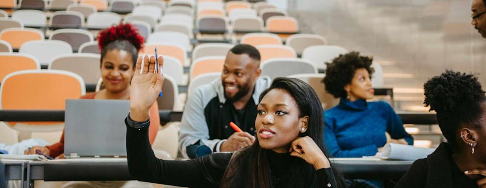 Young female student raising hand during lecture in class