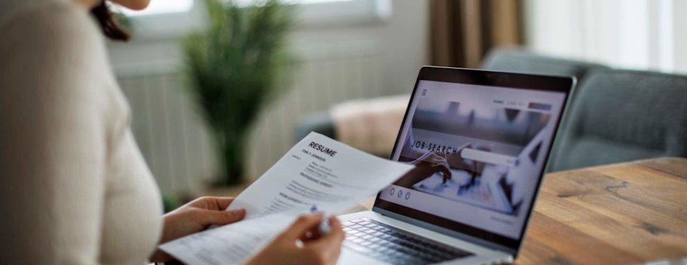 Woman reviewing her resume while searching for jobs online on her laptop