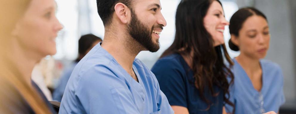 A group of medical school interns listen to a lecture by and unseen professor.