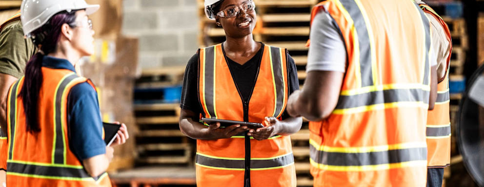 Female warehouse supervisor speaking with a group of employees