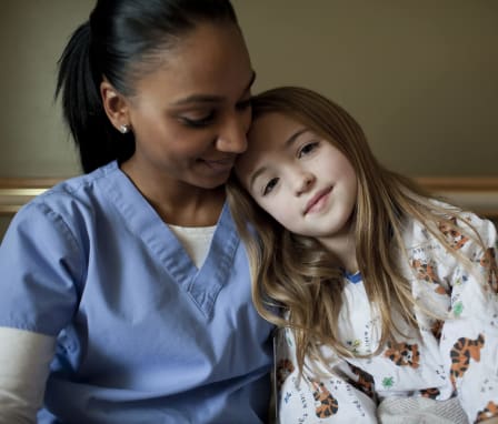 A nurse embraces a young patient.