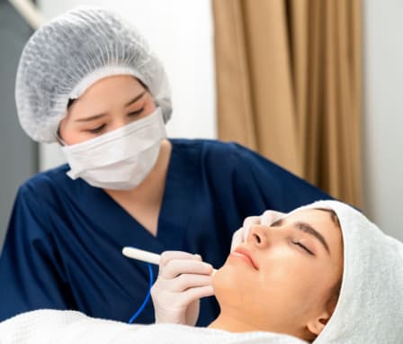 Cosmetologist cleaning or peeling face of young woman in Cosmetologically clinic.