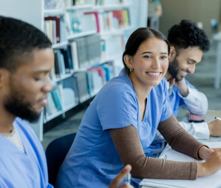 Nursing students smiling and studying together in the library