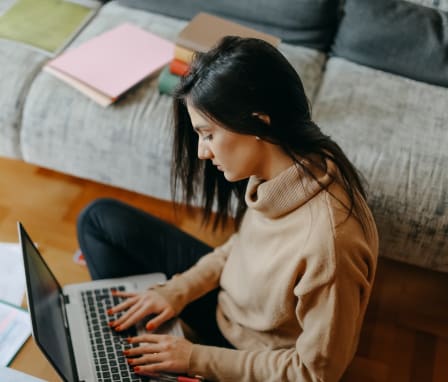 Woman typing on laptop with college application materials