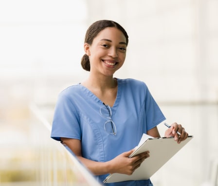 Young nurse smiling while holding a clipboard