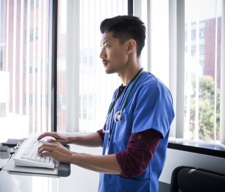 Nurse typing on a computer in a hospital room