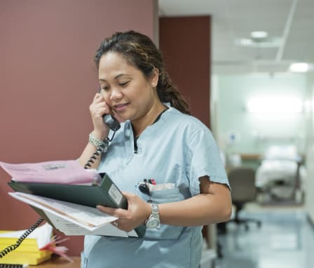 Nurse looking at chart and talking on telephone