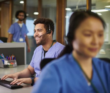 Nurses talking on phone headsets on computers