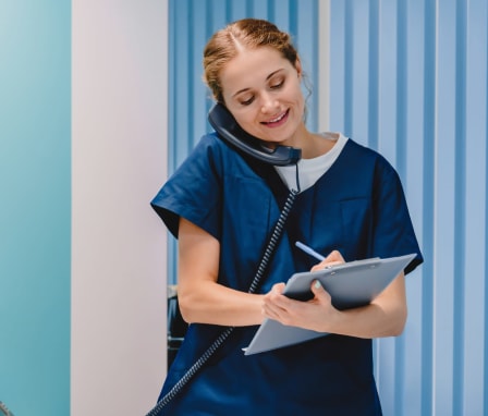 Nurse talking on the phone to a patient and looking at a chart