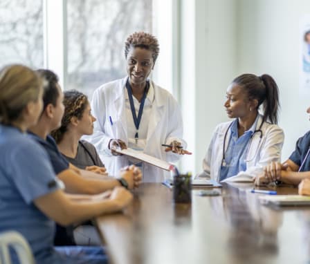 Nurses and doctors sitting at a table together, signing a document