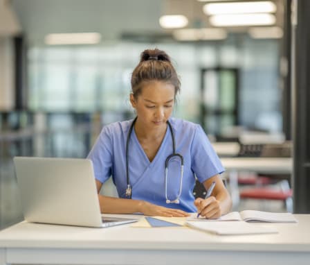 Nursing student studying on laptop in library