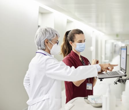 Nurse and doctor wearing masks and looking at a computer monitor in a hospital