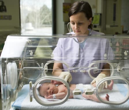 Neonatal nurse checking baby's heartbeat in NICU