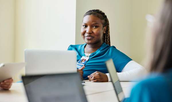 Nurse on laptop talking to other nurses