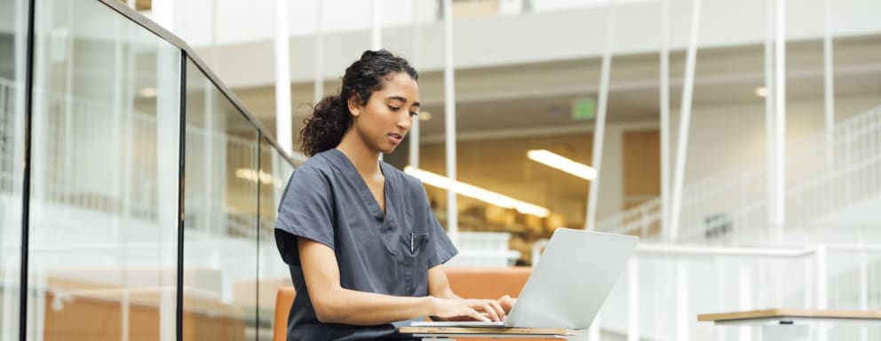 Nursing student working on a laptop at a hospital