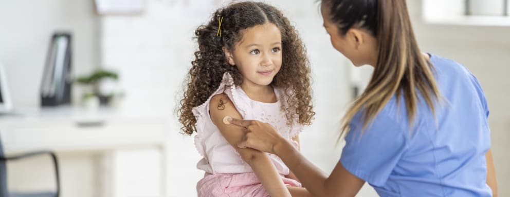 Nurse putting bandage on small child's arm after administering an immunization