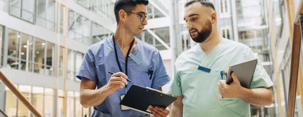 Two male nurses talking in hospital hallway