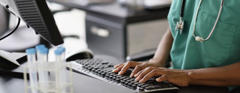 Nurse typing on a computer in a hospital