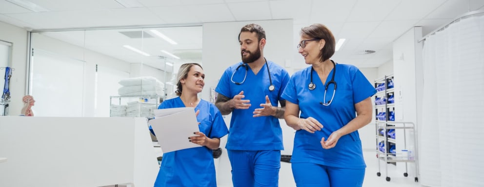 Three nurses walking and talking together in a hospital