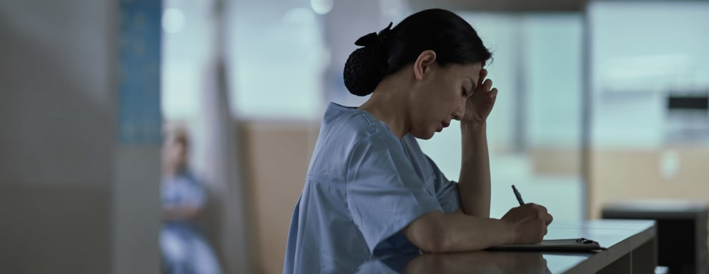 Tired nurse writing in hospital at night