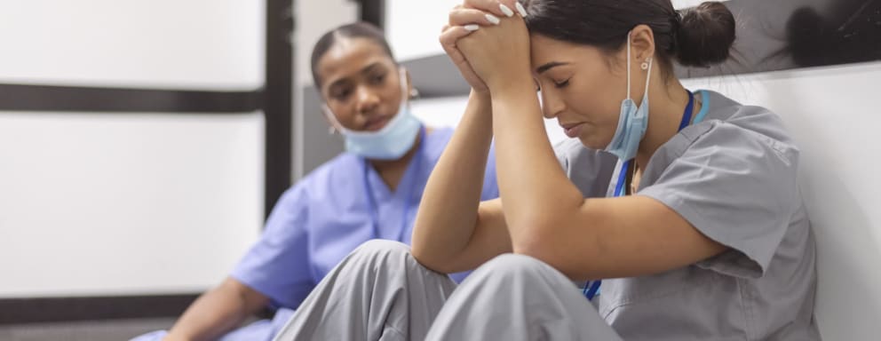 Nurse supporting sad nurse in hallway of hospital