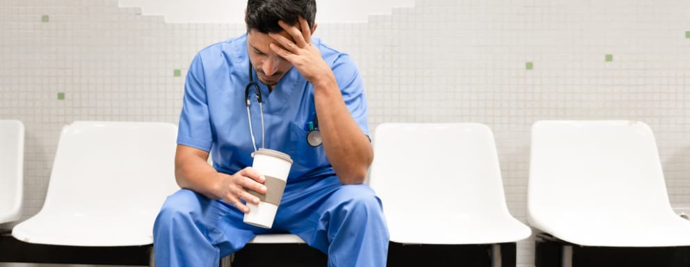 Tired nurse drinking coffee in hospital