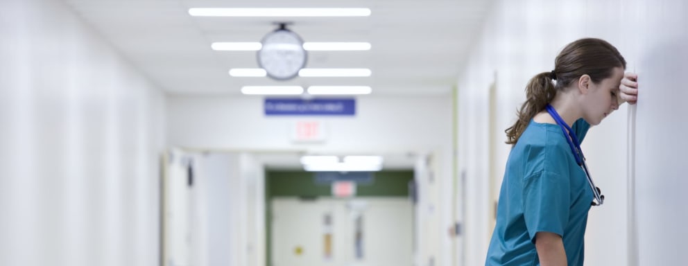 Overwhelmed nurse resting in a hospital hallway