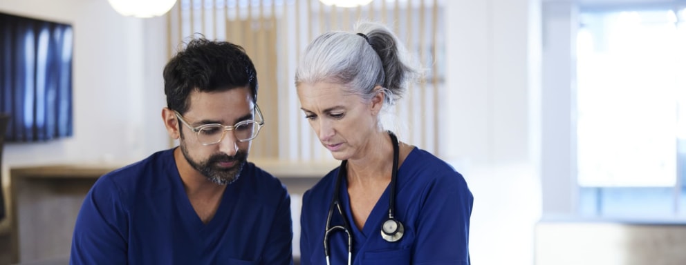 An older and younger nurse looking at a tablet together