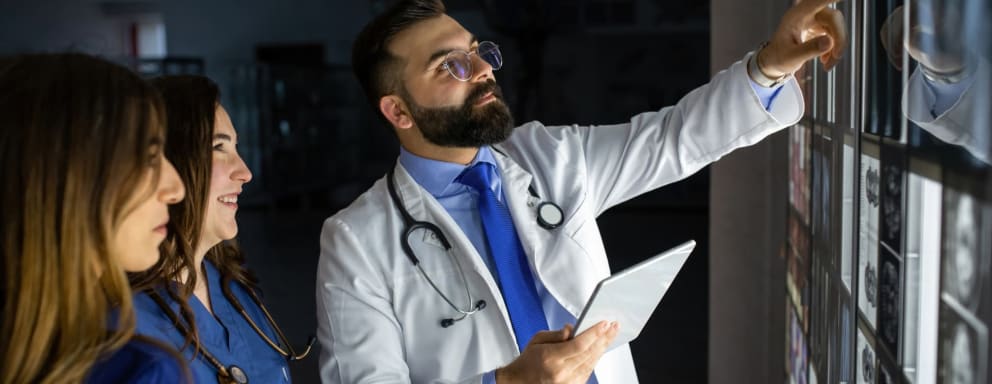 Nurses and doctor inspecting ultrasound images on a lit screen