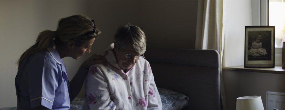 Nurse sitting with elderly patient on bed