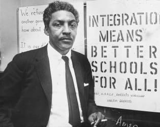 Bayard Rustin, civil rights activist, sitting in front of NAACP posters.