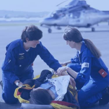 Nurses helping patient on stretcher near helicopter