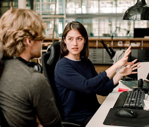 Coworker explaining to colleague while sitting in office. Credit: Maskot / Maskot / Getty Images