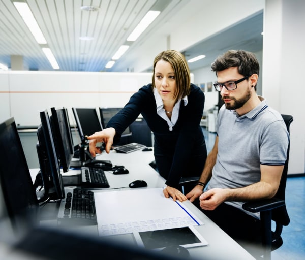 Person helps someone working on a computer